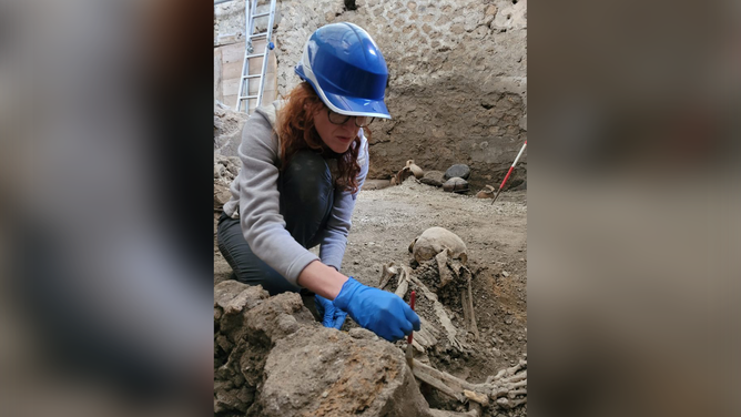 An archeologist is seen collecting data from a skeleton discovered at the Pompeii Archaeological Site.
