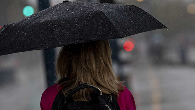 FILE - A woman holds an umbrella.