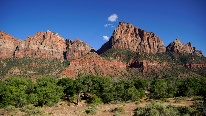 FILE - The evening sun lights the Watchman Tower formation at the entrance to Zion National Park on May 14, 2020 in Springdale, Utah.