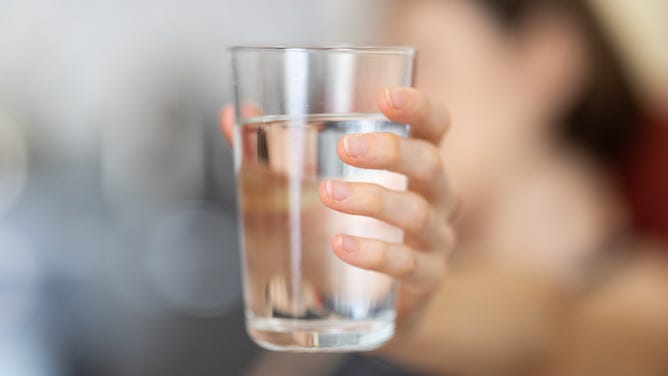 Woman holding glass of water.