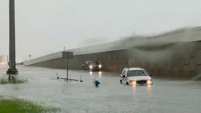 Vehicles attempt to navigate a flooded road in Houston on May 9, 2023.