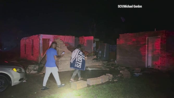 Victims of a likely tornado in Louin, Mississippi, investigate a heavily damaged building.