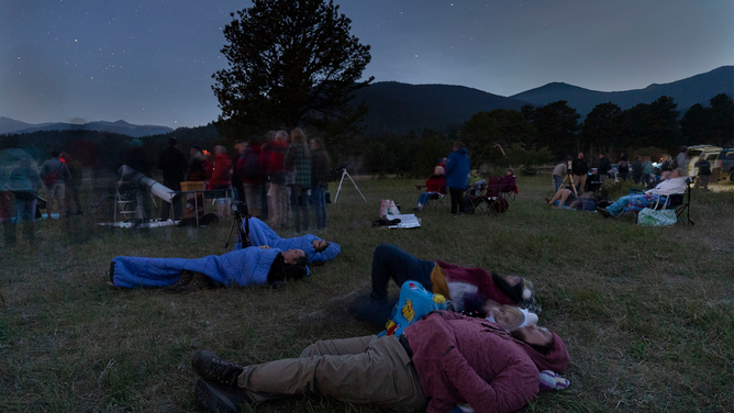FILE - As darkness falls people lie on the ground to view the Perseid meteor shower in Rocky Mountain National Park in Colorado at an astronomy night event on August 12, 2018.