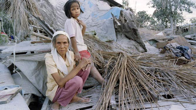 Eight-year old Cynthia Lopez helps her grandmother Lourdes Lino, 68, rebuild their collapsed house, on June 28, 1991 two weeks after powerful eruptions of Mount Pinatubo dumped thousands of tons of volcanic ash in Angeles city, about 20 kilometers east of the volcano. (Photo by Romeo GACAD / AFP) (Photo by ROMEO GACAD/AFP via Getty Images)