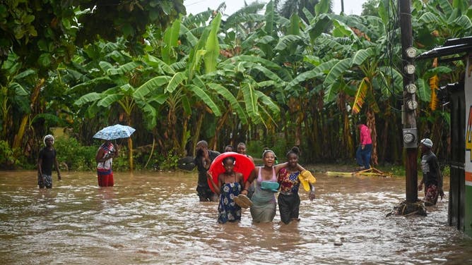 Resident wade through flooded roads in neighborhoods of Petit-Goâve, Haiti, on June 3, 2023, during heavy rainfall in Haiti.