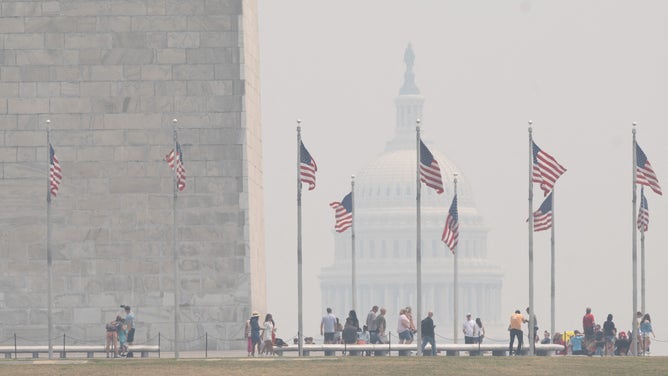 Tourists walk on the National Mall as smoke from wildfires in Canada cause hazy conditions in Washington, DC, on June 7, 2023. Residents of the nation's capital woke Wednesday to an acrid smell and cloudy skies despite sunny weather. Washington authorities warned that the air quality was "unhealthy for people with heart or lung disease, older adults, children and teens" and canceled all outdoor activities in public schools, including sports lessons. (Photo by SAUL LOEB / AFP) (Photo by SAUL LOEB/AFP via Getty Images)