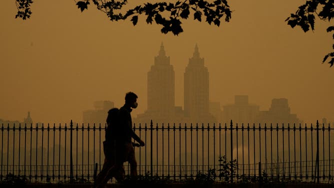 People walk in Central Park as smoke from wildfires in Canada cause hazy conditions in New York City on June 7, 2023. Smoke from Canada's wildfires has engulfed the Northeast and Mid-Atlantic regions of the US, raising concerns over the harms of persistent poor air quality. (Photo by TIMOTHY A. CLARY / AFP) (Photo by TIMOTHY A. CLARY/AFP via Getty Images)