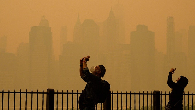 People take photos of the sun as smoke from the wildfires in Canada cause hazy conditions in New York City on June 7, 2023.