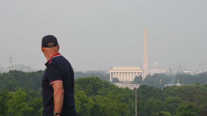 WASHINGTON, DC - JUNE 07: A man looks on as gaze blankets over monuments on the National Mall on June 7, 2023 in Washington, DC. Air pollution alerts were issued across the United States as harmful smoke wafted south from more than a hundred wildfires burning in Quebec, Canada. (Photo by Chen Mengtong/China News Service/VCG via Getty Images)