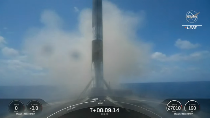 A SpaceX Falcon 9 booster stands tall after landing on a droneship in the Atlantic Ocean. 