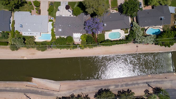 A section of the Central Arizona Project, a series of aqueducts and tunnels designed to bring water from the Colorado River to central and southern Arizona, flows past single family homes with swimming pools in Phoenix, Arizona, on May 9, 2023.