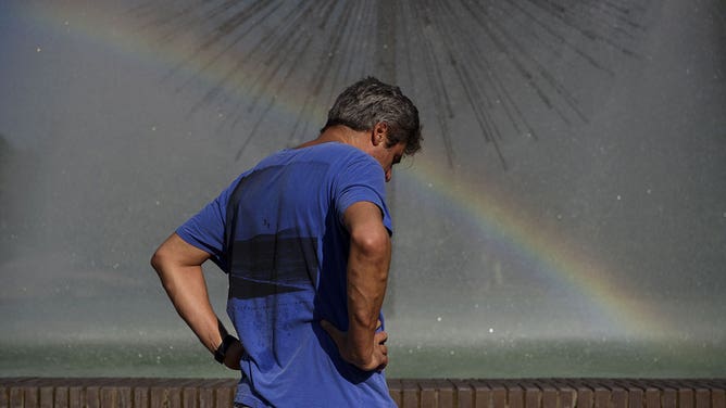 FILE - A person cools off near a fountain during a heatwave in Houston, Texas, U.S., on Wednesday, June 16, 2021.