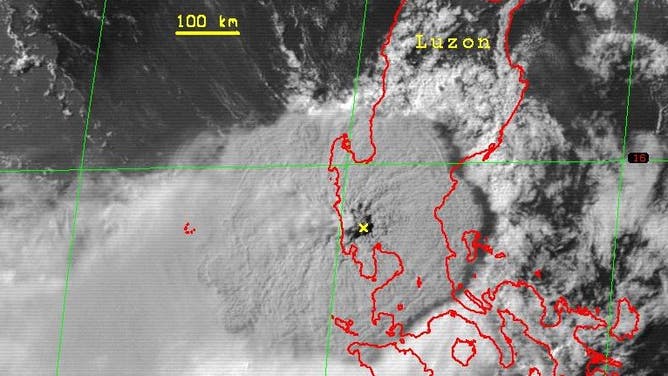 Satellite image of Mount Pinatubo eruption cloud about 2.25 hours after the onset of the climactic phase of the eruption, June 15, 1991. The yellow 'x' marks the volcano. The enormous round shape of the eruption cloud resulted from the pass of tropical storm Yunya across the Philippines about 75 km northeast of Pinatubo during the eruption. Typhoon Yunya made landfall at 0800 June 15 then decreased in intensity to a tropical storm. Owing at least in part to the atypical lower- and mid-level wind regime spawned by the passing storm, ash and larger particles were widely distributed in all directions immediately around the erupting volcano. Most of the ash was blown to the west southwest over a broad area across the South China Sea; ash dusted parts of Indochina, more than 1,200 km away.