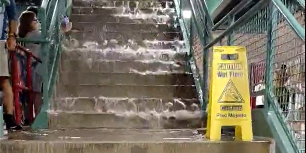 Baseball fans at Fenway Park wade through floodwater as storms force