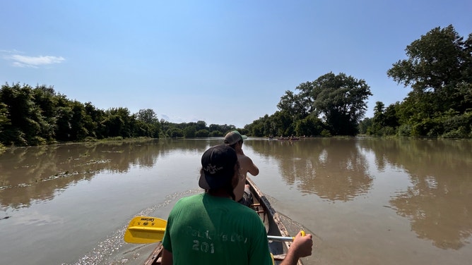 Pitchfork Farm co-owner Eric Seitz and farm staff paddle through the flooded vegetable fields in Vermont.