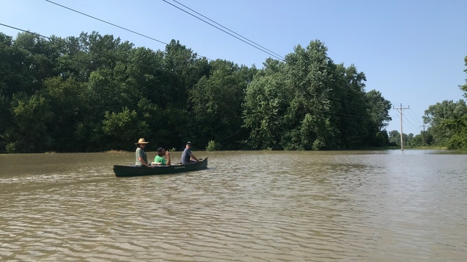 Pitchfork Farm co-owner Eric Seitz and farm staff paddle through the flooded vegetable fields in Vermont.