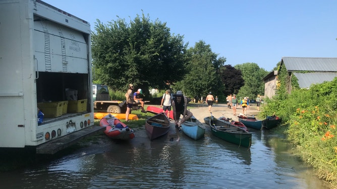Pitchfork Farm co-owner Eric Seitz and farm staff paddle through the flooded vegetable fields in Vermont.