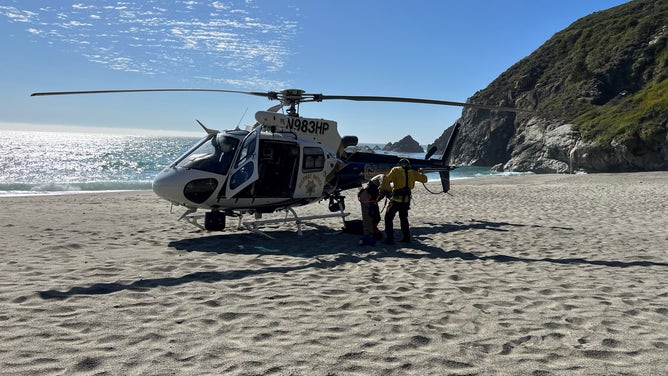 A woman and her dog needed to be rescued after becoming stranded on a cliff in Big Sur, California. This image shows a California Highway Patrol helicopter on the beach near Gamboa Point.