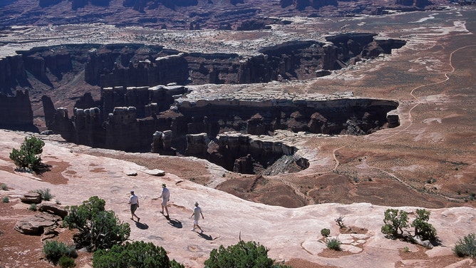 Hikers at Grand View Point in the Isle of Sky district at Canyonlands National Park in Utah.