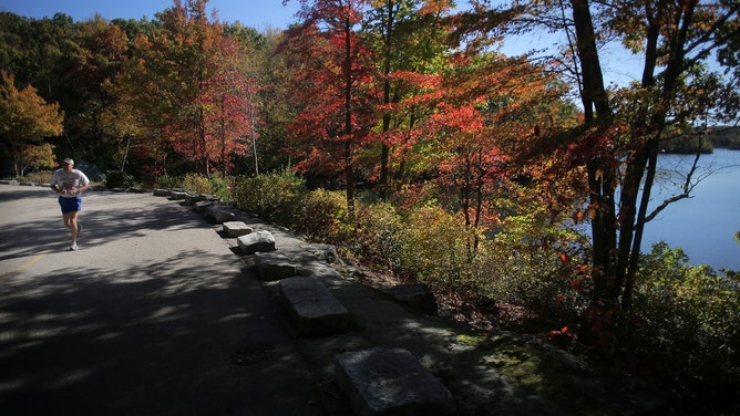 LINCOLN, RI - OCTOBER 14: A jogger passes Olney Pond inside Lincoln Woods State Park in Lincoln, RI on Oct. 14, 2020. Rhode Island's beautiful parks provide solace and recreation during the COVID-19 pandemic. (Photo by Lane Turner/The Boston Globe via Getty Images)