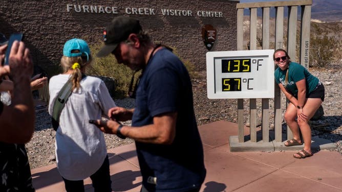 Tourists stop at the Furnace Creek Visitors Center to take pictures in front of the thermometer showing the current extreme record breaking temperature of 135 degrees Fahrenheit in Death Valley National Park, California Saturday July 10, 2021.