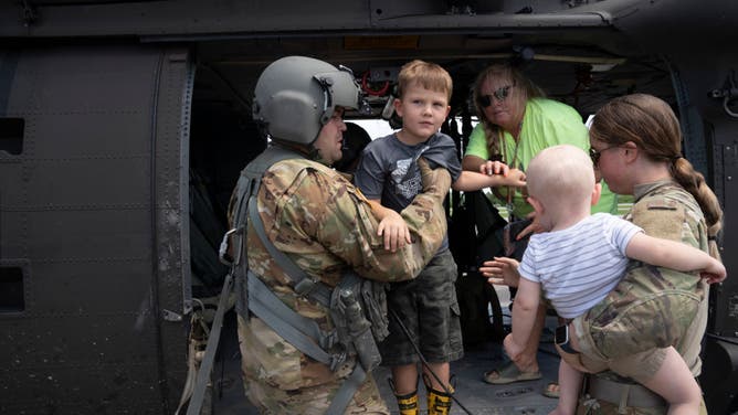  Sergeant Thorin Brant of the Kentucky National Guard carries children from a helicopter at the Wendell H. Ford Regional Airport after being airlifted from South Fork, Kentucky during a recon and rescue mission in Breathitt County, near Hazard, Kentucky. 