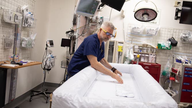Dr. Frank Lovecchio demonstrates an inflatable pool-like device that can be filled with ice, used in the emergency medicine unit at Valleywise Hospital during extreme heat in Phoenix, Arizona on July 11, 2023.