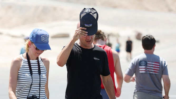 Tourists walk back to their vehicle at Zabriskie Point during a heat wave in Death Valley National Park in Death Valley, California, on July 16, 2023. Tens of millions of Americans braced for more sweltering temperatures Sunday as brutal conditions threatened to break records due to a relentless heat dome that has baked parts of the country all week. By the afternoon of July 15, 2023, California's famous Death Valley, one of the hottest places on Earth, had reached a sizzling 124F (51C), with Sunday's peak predicted to soar as high as 129F (54C). Even overnight lows there could exceed 100F (38C).