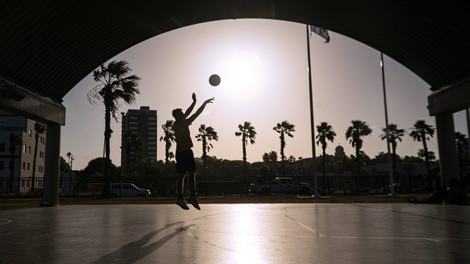 A resident plays basketball at the Texas A&M Corpus Christi Islander Courts during a heat wave in Corpus Christi, Texas, on Thursday, July 20, 2023.