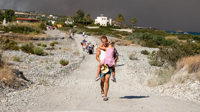 RHODES ISLAND, GREECE - JULY 22: Tourists are evacuated as huge wildfire rages across Greece's Rhodes island on July 22, 2023. Thousands of tourists were evacuated from hotels on the southeastern coast of Rhodes island as a huge wildfire that had been burning on the island since Tuesday morning continued to spread quickly. Firefighters, as well as fire extinguisher aircraft, are battling the blazes against strong winds.