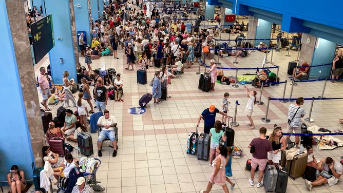 Tourists wait in the airport's departure hall as evacuations are underway due to wildfires, on the Greek island of Rhodes on July 23, 2023. Locals and tourists fled hotspots on Rhodes, as firefighters battled a blaze that had sparked the country's largest-ever fire evacuation. Firefighters were bracing for high winds that have been forecast for the afternoon and that could hamper their efforts.