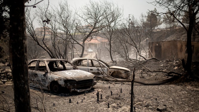 24 July 2023, Greece, Kiotari: Burned cars in the village of Kiotari. Forest fires rage in Rhodes and other parts of Greece