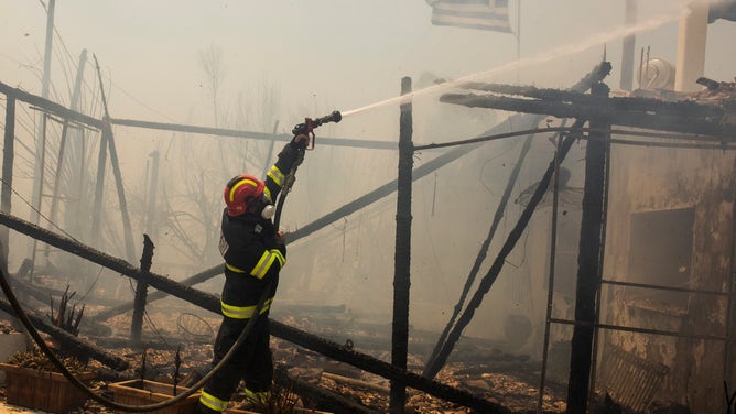 24 July 2023, Greece, Gennadi: Romanian firefighters try to extinguish a fire that broke out in a house near the village of Gennadi. Forest fires rage in Rhodes and other parts of Greece.