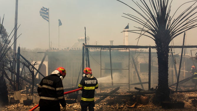 24 July 2023, Greece, Gennadi: Romanian firefighters try to extinguish a fire that broke out in a house near the village of Gennadi. Forest fires rage in Rhodes and other parts of Greece.