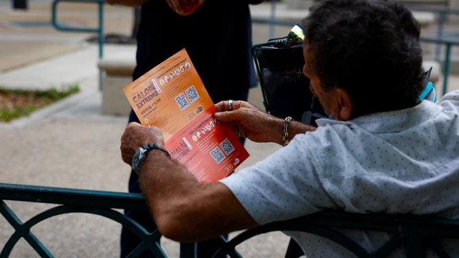 A Miami-Dade County Homeless Trust representative distributes shelter information during a heat wave in Miami, Florida, US, on Tuesday, July 25, 2023. Heat advisories and excessive heat warnings stretch from California's Central Valley to Miami.