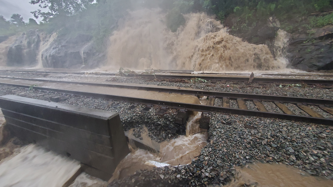 Water rushes down a hill after torrential rain in New York on Sunday, July 9, 2023.