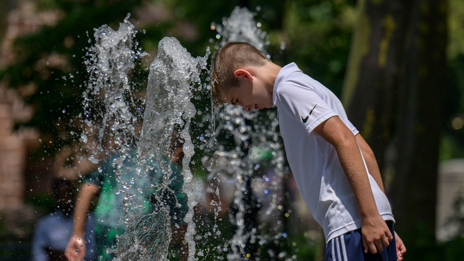 A boy cools off in a public fountain at a park as temperatures begin to rise on July 26, 2023 in New York.