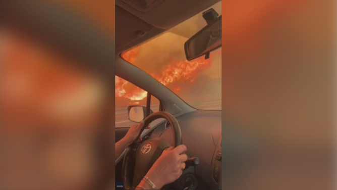 This image shows flames surrounding a mother and daughter who were driving in their car in Sicily, Italy, while escaping a wildfire.