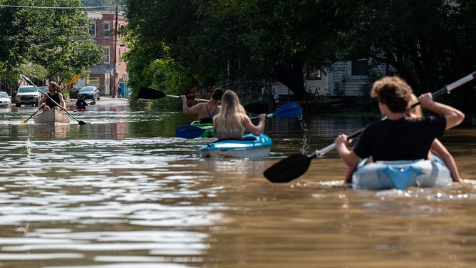 People kayak up and down the flooded waters of Elm Street on July 11, 2023 in Montpelier, Vermont.