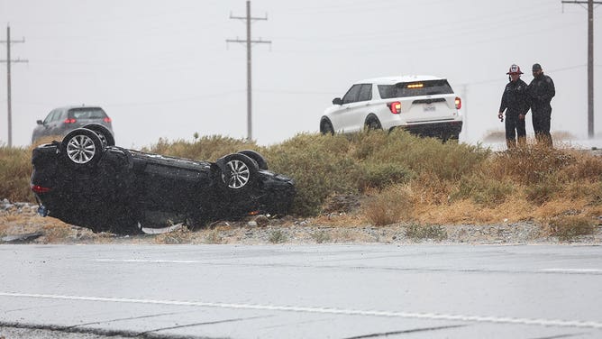 First responders keep watch near a vehicle that flipped over during rainfall from approaching Tropical Storm Hilary on August 20, 2023 near Palm Springs, California.