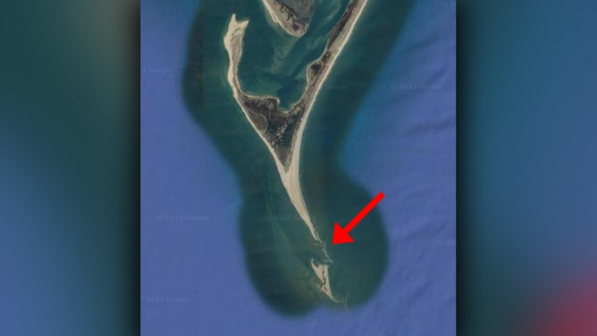 A satellite image of Cape Lookout shows a sandy beach coming to a sharp point and jetting southward. A small island can be seen south of that point, and a red arrow indicates the area between the island and the point.
