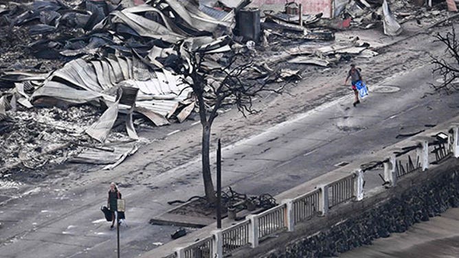 An aerial image taken on August 10, 2023 shows a person walking down Front Street past destroyed buildings burned to the ground in Lahaina in the aftermath of wildfires in western Maui, Hawaii.