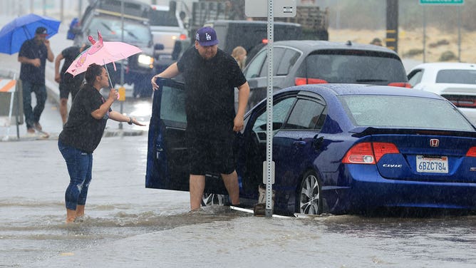 Motorists deal with a flooded road and stuck in vehichles during heavy rains from Tropical Storm Hilary in Palm Springs, California, on August 20, 2023.