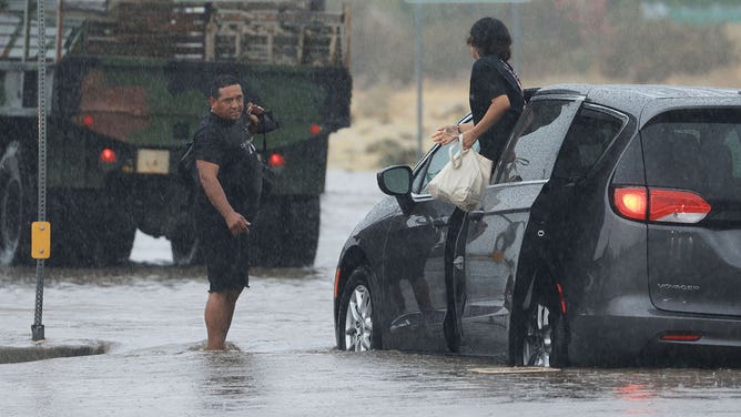Motorists leave their vehicle stuck on a flooded road during heavy rains from Tropical Storm Hilary in Palm Springs, California, on August 20, 2023.