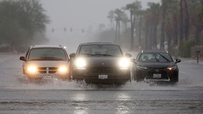 Vehicles drive along a flooded street as Tropical Storm Hilary approaches on August 20, 2023 in Palm Springs, California.