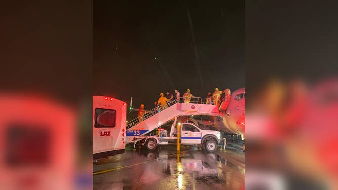 In the pouring rain, Orange County Fire Authority crews help passengers off Alaska Airlines flight 188 at John Wayne Airport in Santa Ana, California.