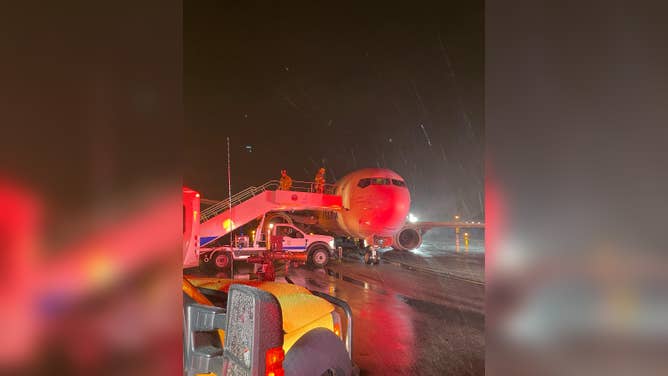 In the pouring rain, Orange County Fire Authority crews help passengers off Alaska Airlines flight 188 at John Wayne Airport in Santa Ana, California.