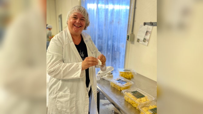A woman with cut and packaged pineapples.