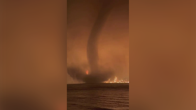 A waterspout is seen spinning in front of a massive wildfire in Canada.