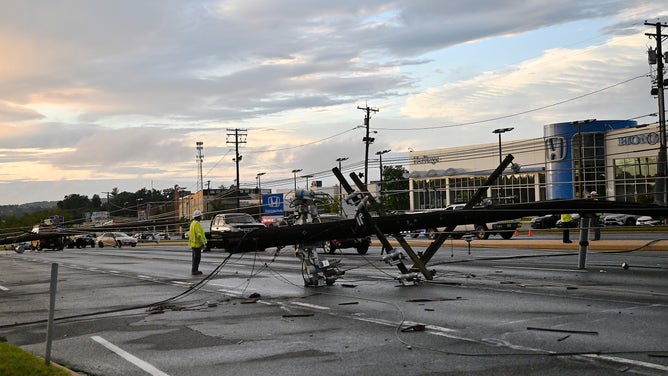 A utility worker stands near a downed utility pole in Westminster, Maryland, on Monday, August 7, 2023.